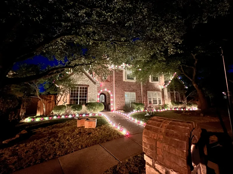 Christmas light installation by Christmas Lights Experts DFW &mdash; warm white C9 roofline on a brick home with a red-and-white lit walkway