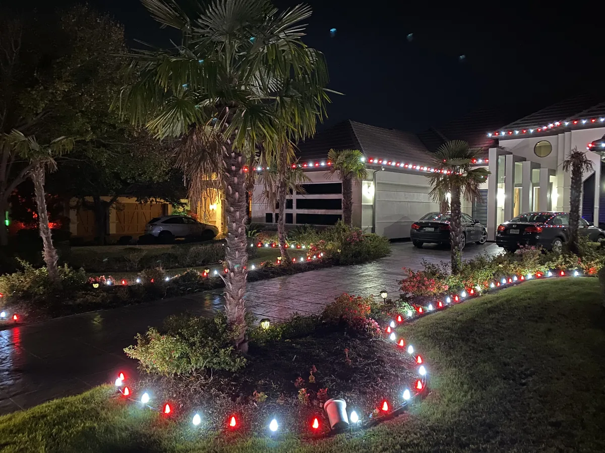 Christmas light installation Frisco TX — red and white roofline and path lighting on a stucco home