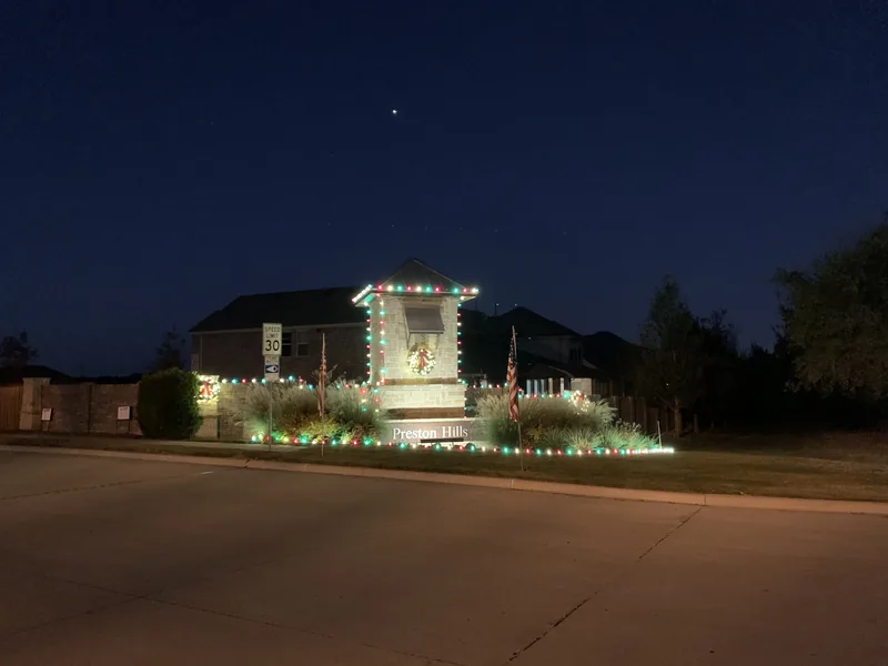 HOA Christmas light installation DFW — warm white community entrance lighting at night