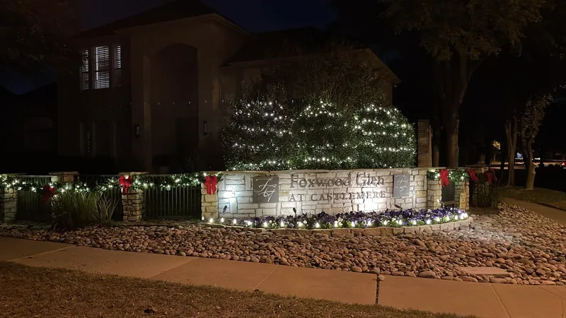 HOA Christmas light installation DFW — lit monument entrance for a master-planned community