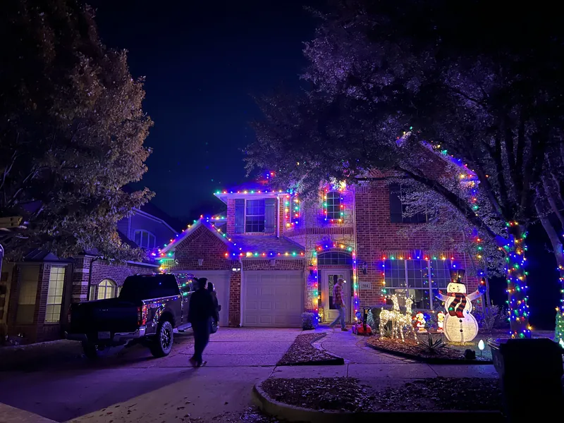 Christmas light installation McKinney TX — multicolor roofline with lit yard decorations on a brick home