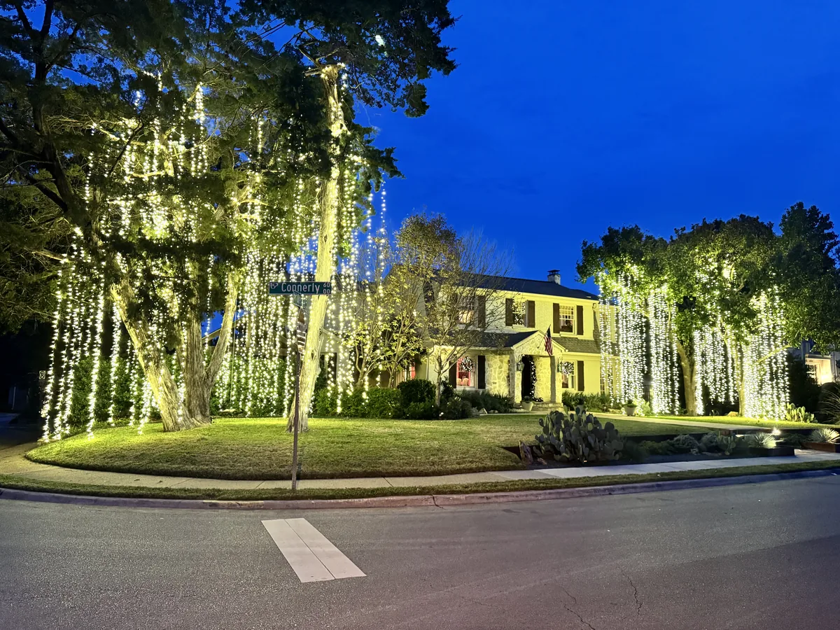 Christmas light installation Park Cities TX — warm white roofline and lit wreaths on a brick estate