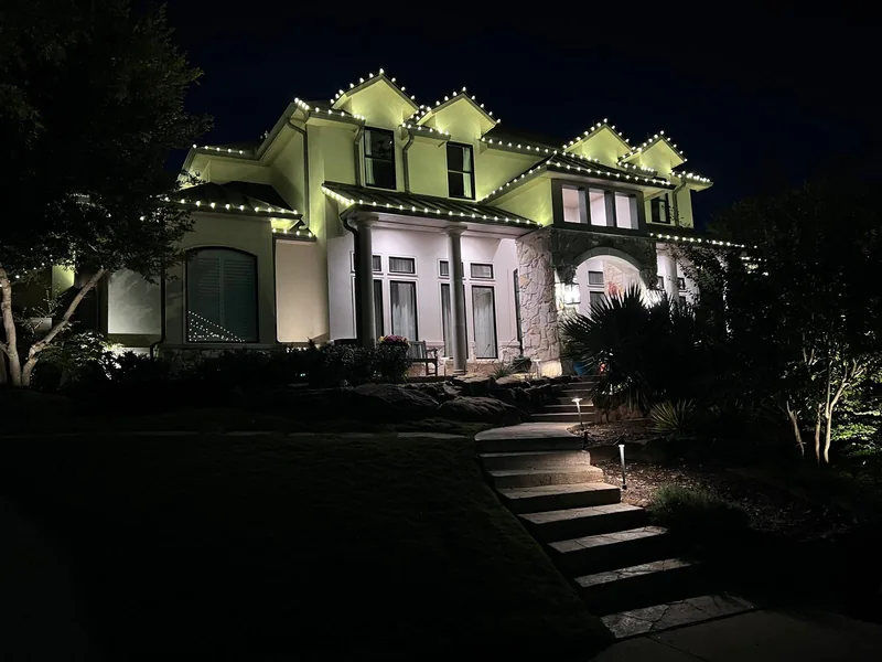 Christmas light installation by Christmas Lights Experts DFW &mdash; warm white C9 roofline on a large two-story home at dusk